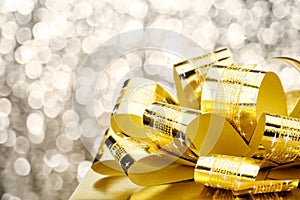 Close up Golden present box with big bow at bokeh white blur background, Leave space on top to adding your content photo